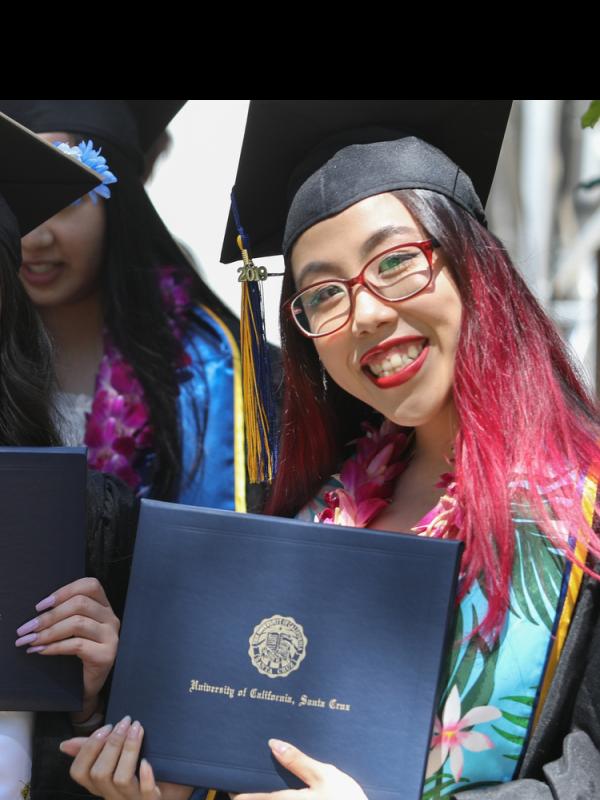 two students holding degrees