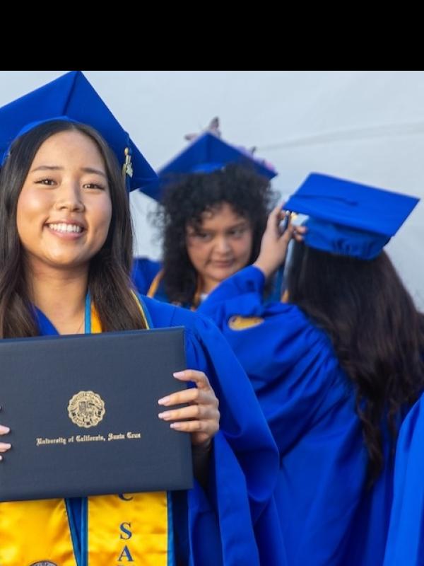 Graduating student proudly holding up diploma