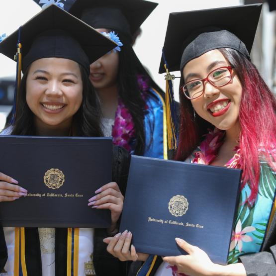 two students holding degrees
