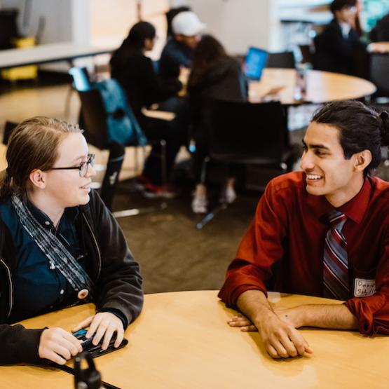 two students sitting at a table talking