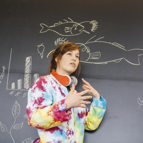 Student explaining scientific principles in front of a blackboard