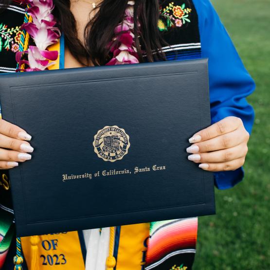 An individual holding a folder with the words "University of California, Santa Cruz" on it