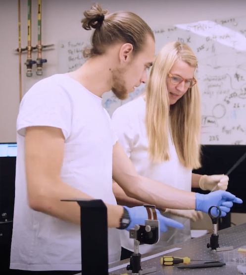 two students in gloves working with electronics in a lab